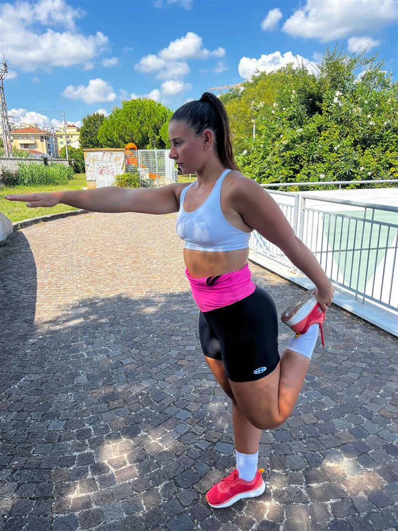 Standing quadriceps stretch, holding the foot behind the body and reaching forward with the other arm